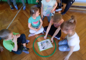 Czworo dzieci układa w obręczy wiosenne puzzle